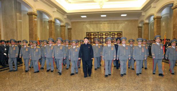 Kim Jong-un geht vor einer Reihe von Militäroffizieren in einem großen Saal entlang.
