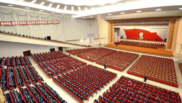 Eine große Versammlung in Nordkorea mit einem Porträt von Kim Il-sung auf der Bühne.