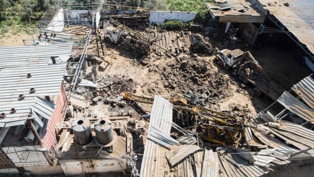 Ein zerstörtes Gelände mit Trümmern, Fahrzeugen und beschädigten Gebäuden.