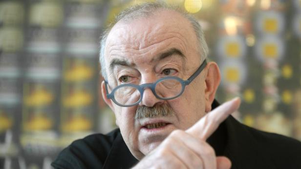 Ein Mann mit Brille und Schnurrbart gestikuliert mit dem Finger.