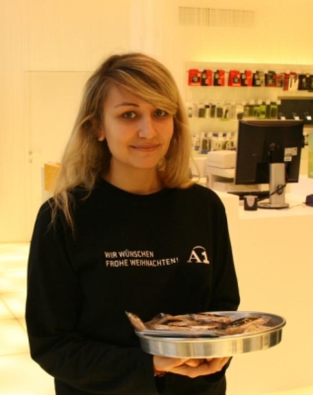 Eine Frau im A1-Shirt hält eine Platte mit eingelegten Heringen.