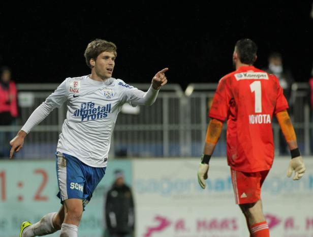 Ein Fußballspieler jubelt und zeigt auf den gegnerischen Torwart Novota.