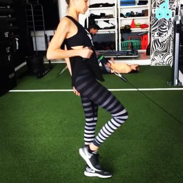 Eine Frau trainiert mit einem Kabelzug in einem Fitnessstudio.