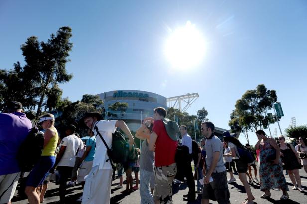 Eine Menschenmenge versammelt sich vor der Hisense Arena unter strahlendem Sonnenschein.