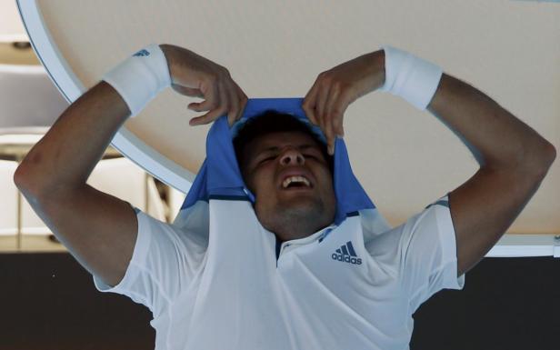 Ein Tennisspieler zieht sein Shirt über den Kopf.