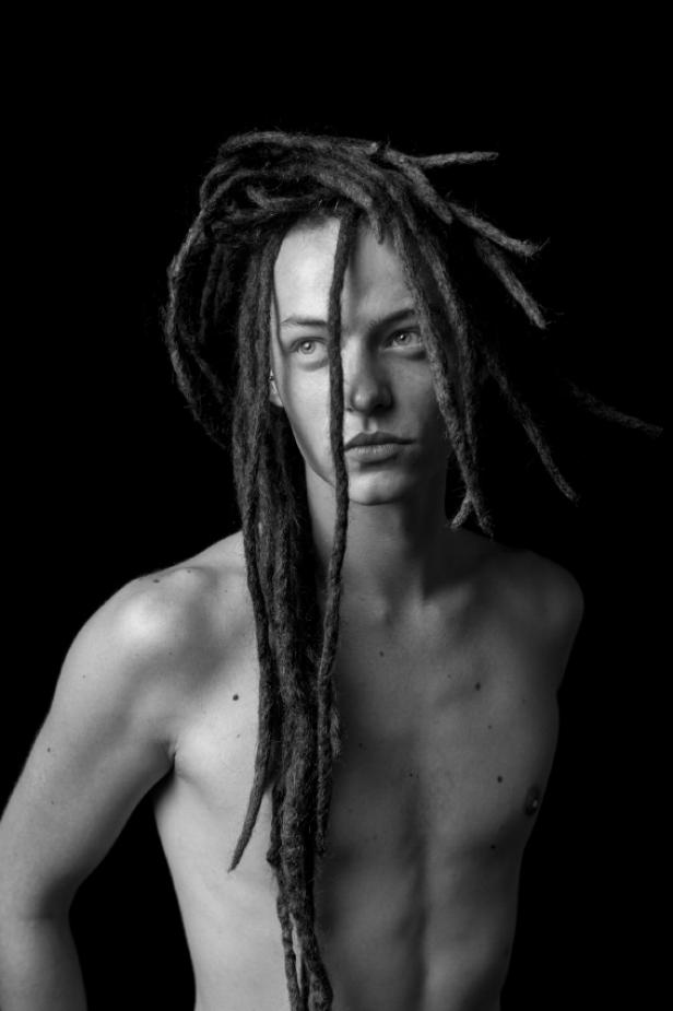 Ein junger Mann mit Dreadlocks in einer Schwarzweißaufnahme.