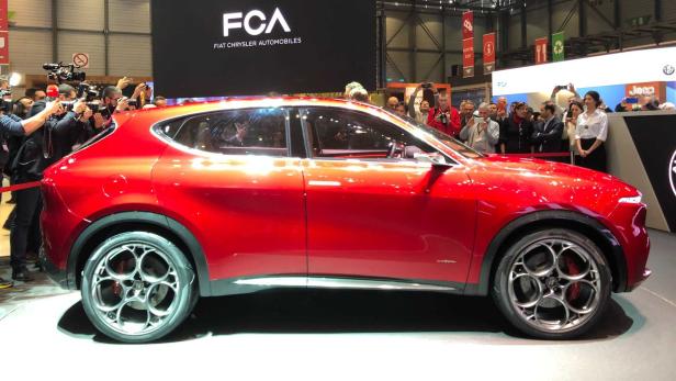 Ein roter Alfa Romeo Tonale wird auf einer Automobilmesse von Fotografen umringt.