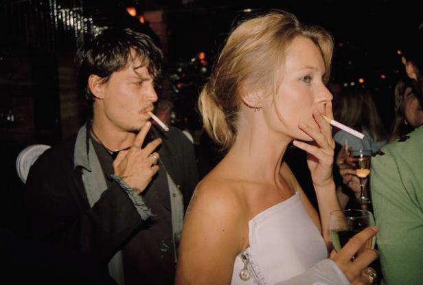 Johnny Depp und Kate Moss rauchen in einem dunklen Raum Zigaretten.