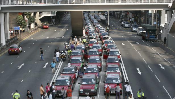 Eine lange Schlange roter Taxis staut sich auf einer Straße in Hongkong.