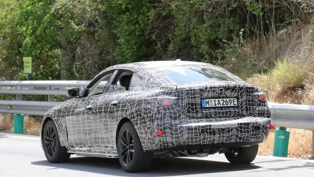 Ein getarntes Elektroauto von BMW bei Testfahrten auf einer Landstraße.