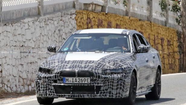 Ein Prototyp eines BMW mit Tarnmuster fährt auf einer Straße.