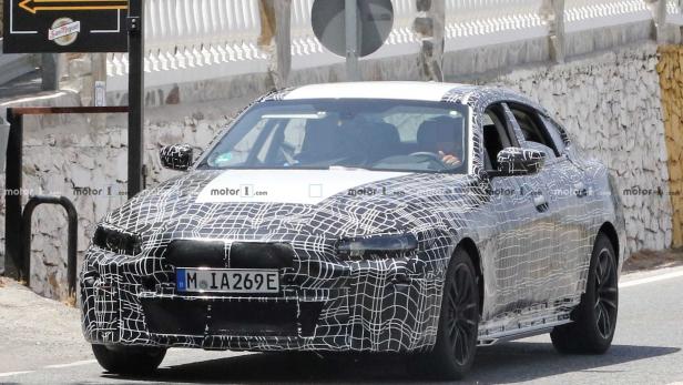 Ein getarntes Auto, vermutlich ein neuer BMW, fährt auf einer Straße.