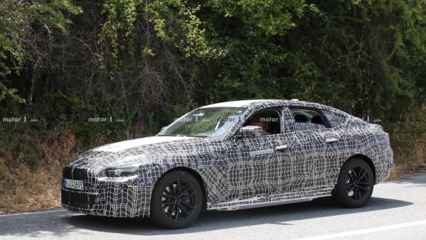 Ein Prototyp eines BMW-Fahrzeugs mit Tarnmuster fährt auf einer Straße.