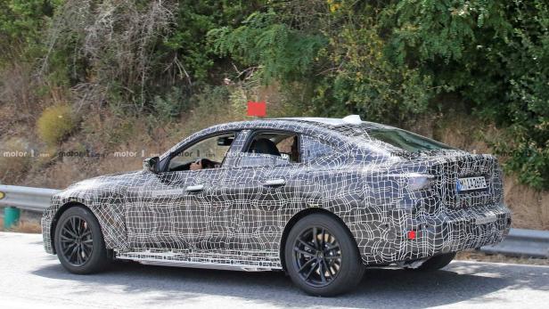 Ein Prototyp eines BMW-Fahrzeugs mit Tarnmuster auf einer Straße.