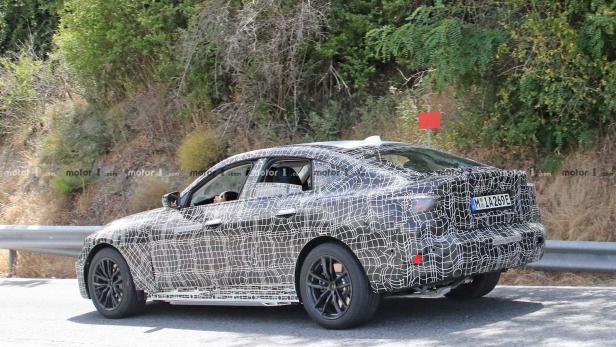 Ein getarntes BMW-Fahrzeug fährt auf einer Straße.