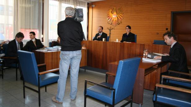 Zivilprozess gegen Simandl, Verteidiger, Richterin… Eine Gerichtsverhandlung mit Richtern und Anwälten wird gefilmt.