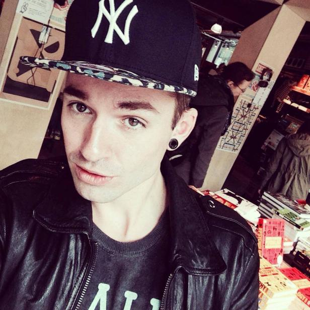 Ein junger Mann mit New-York-Yankees-Kappe und schwarzer Lederjacke macht ein Selfie.
