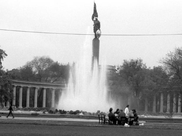 Eine Gruppe von Menschen sitzt an einem Tisch vor dem Sowjetischen Ehrenmal im Tiergarten in Berlin.