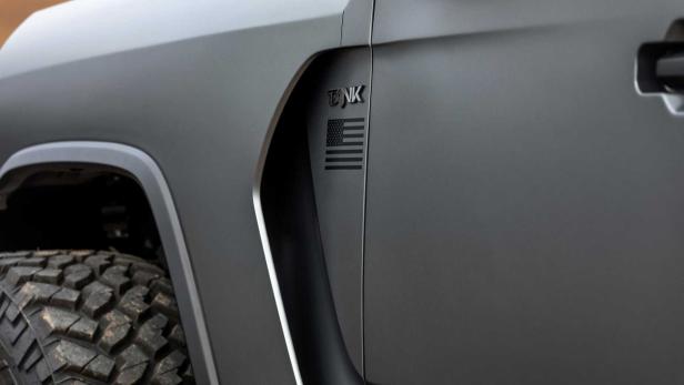 Detailansicht eines grauen Geländewagens mit „TANK“-Logo und US-Flagge.