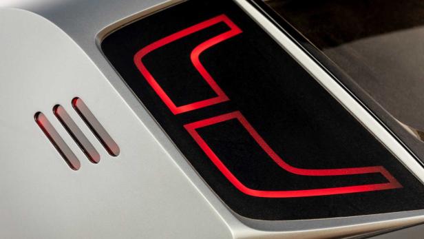 Nahaufnahme eines Rücklichts mit roter LED-Beleuchtung an einem silbernen Fahrzeug.