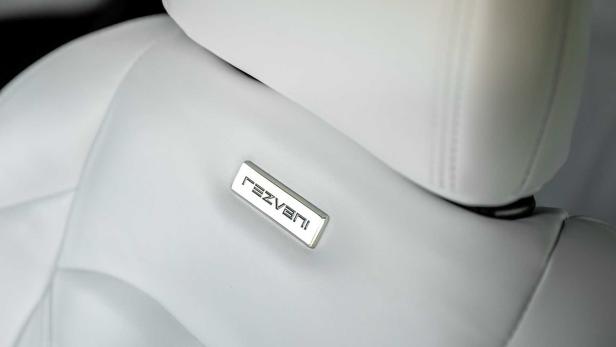 Detailaufnahme eines weißen Ledersitzes mit dem „Rezvani“-Logo.
