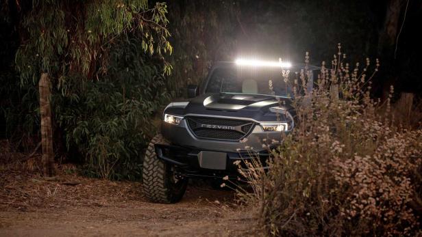 Ein grauer Rezvani Tank Offroader steht im Gelände mit eingeschalteter Lichtleiste.