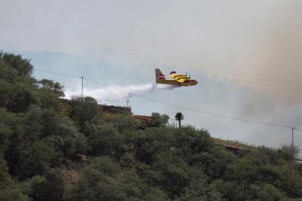 Plane drops water to fight a forest fire seen in the village of Galdar on the Canary Island of Gran Canaria
