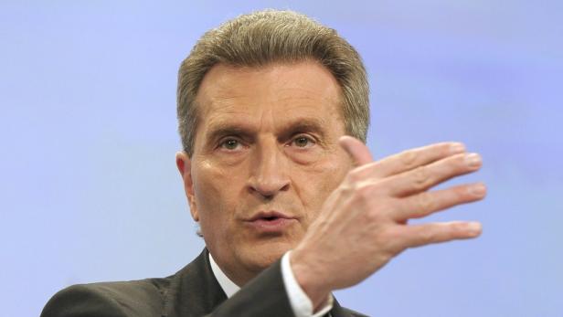 Ein Mann im Anzug gestikuliert vor einem hellblauen Hintergrund.