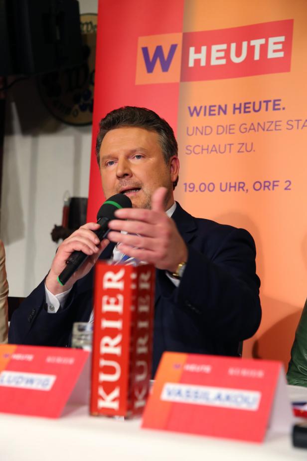 Ein Mann spricht bei einer Pressekonferenz, im Hintergrund ein „Wien Heute“-Banner.