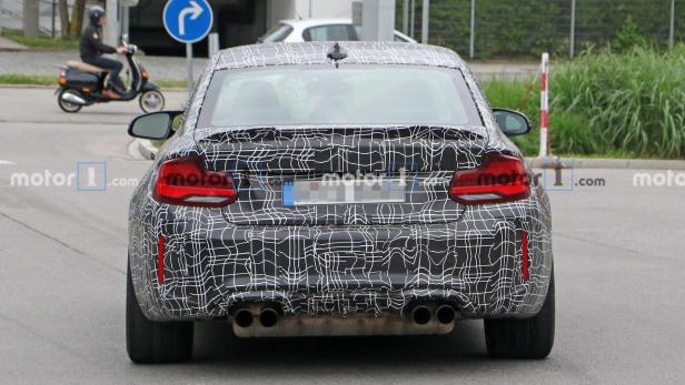 Die Rückansicht eines getarnten BMW M2 mit vier Auspuffrohren.