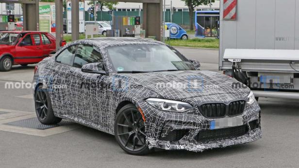 Ein mit einem Tarnmuster beklebter BMW steht auf einer Straße.