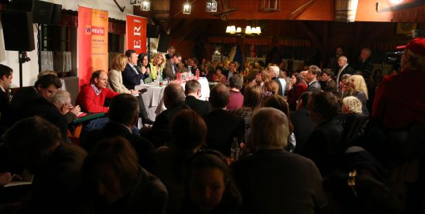 Eine Podiumsdiskussion mit Publikum in einem holzvertäfelten Raum.