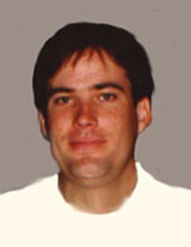 Porträt eines Mannes mit dunklen Haaren und einem weißen Hemd.