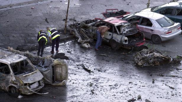 Nach einem Bombenanschlag inspizieren Polizisten zerstörte Fahrzeuge.