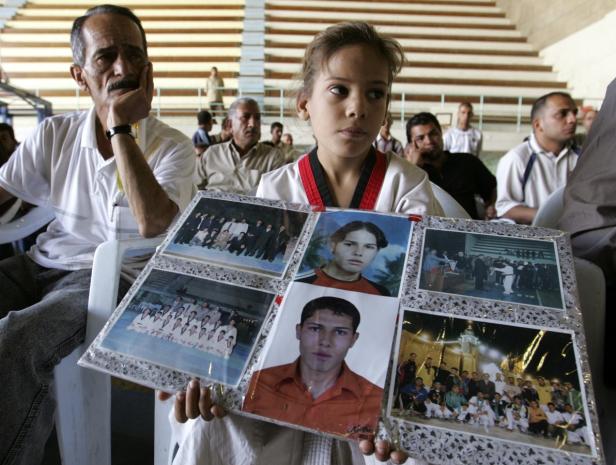Ein Mädchen im Karateanzug hält ein Fotoalbum mit Bildern von jungen Männern.