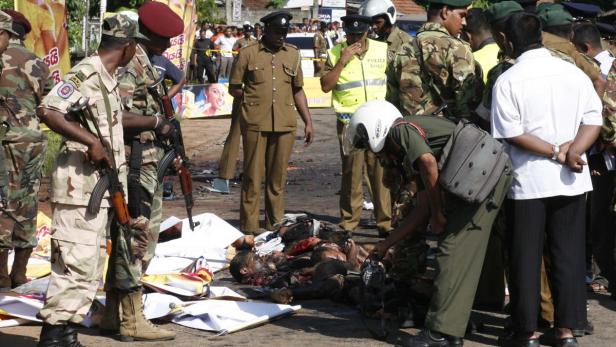 Nach einem Bombenanschlag stehen Soldaten und Polizisten um die Leichen von Opfern.