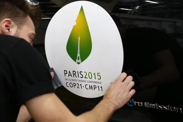 An employee installs a sticker with the logo of the upcoming COP21 Climate Change Conference on a Nissan LEAF electric car in Boulogne-Billancourt, near Paris