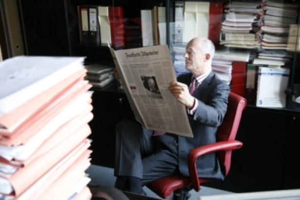 Ein Mann im Anzug liest eine Zeitung in seinem Büro.