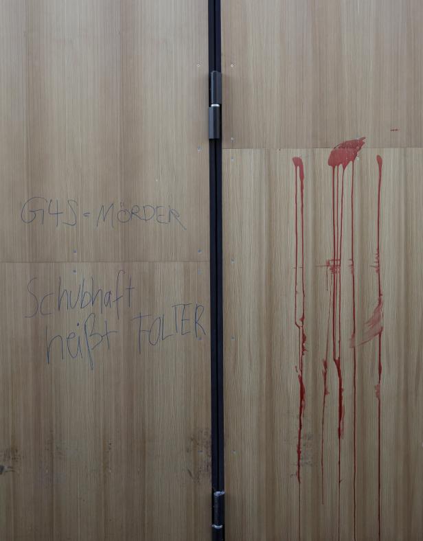 Eine Holztür ist mit Graffiti und Bluttropfen bedeckt.