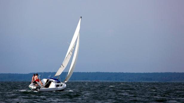 Ein Segelboot mit zwei Personen segelt auf dem Wasser.