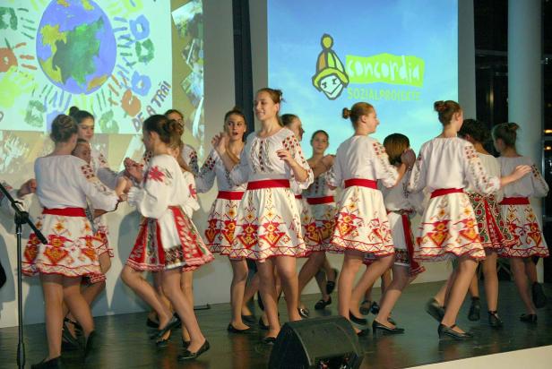 Eine Gruppe junger Frauen in Trachten tanzt auf einer Bühne.