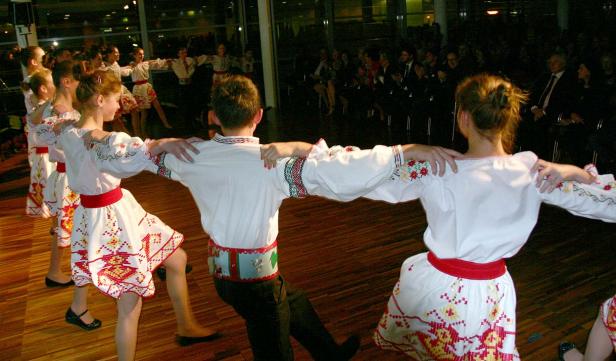 Eine Gruppe von Kindern führt einen traditionellen Tanz in Trachten vor Publikum auf.
