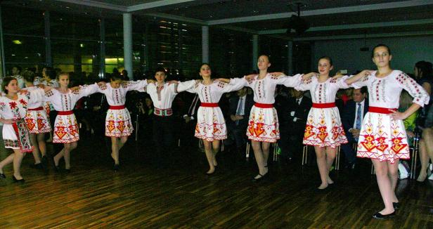 Eine Gruppe junger Tänzerinnen und ein Tänzer in traditionellen ukrainischen Trachten führen einen Tanz auf.