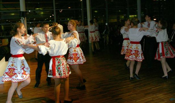 Eine Gruppe von Jugendlichen tanzt in traditionellen ukrainischen Trachten im Kreis.