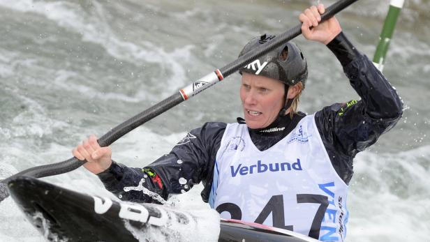 Eine Frau paddelt in einem Kajak durch Wildwasser.