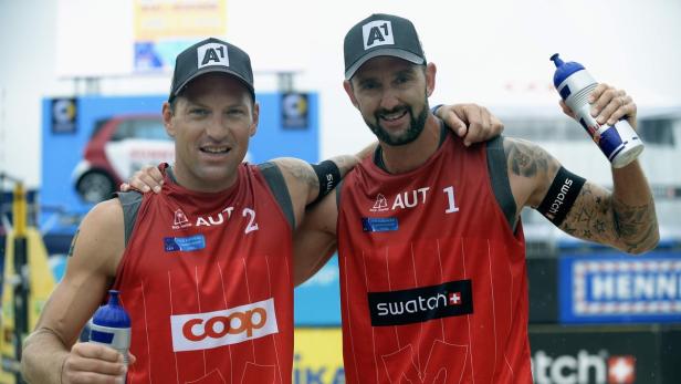 Zwei österreichische Beachvolleyballspieler posieren mit Wasserflaschen für ein Foto.