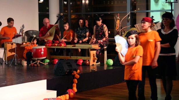 Eine Gruppe von Menschen spielt traditionelle chinesische Musik auf einer Bühne.