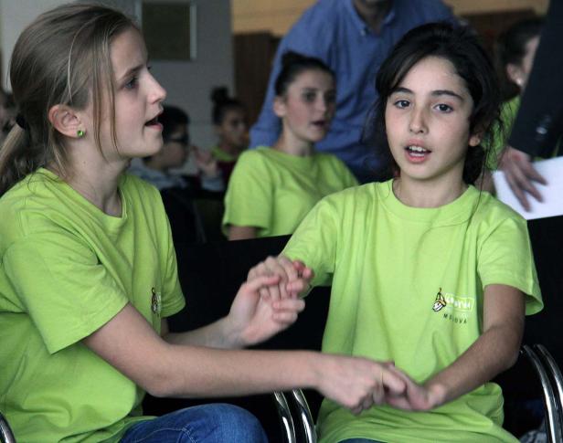 Zwei Mädchen in grünen T-Shirts halten Händchen.