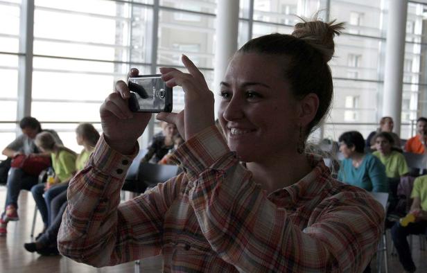 Eine Frau macht mit ihrem Smartphone ein Foto von einer Gruppe von Menschen.