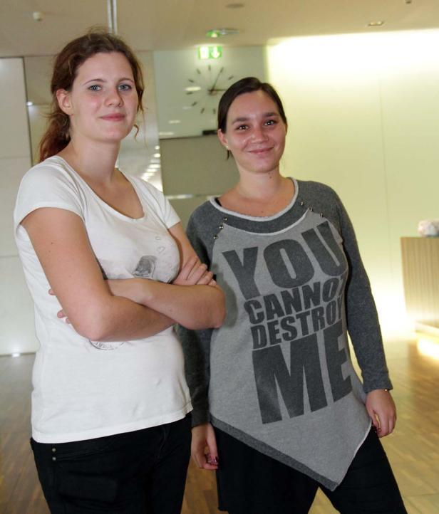 Zwei junge Frauen stehen nebeneinander in einem Innenraum.